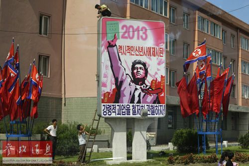 25日,几名工人在平壤街头安装宣传牌,为即将到来的朝鲜战争停战60周年纪念活动做准备。