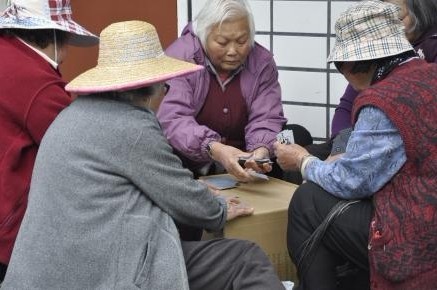 一群华人老太在广场上玩扑克。美国《侨报》