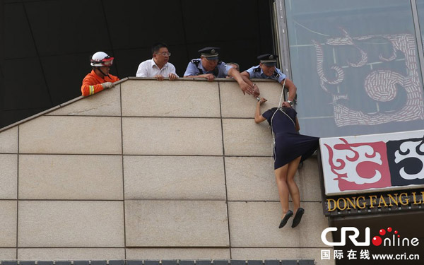 2013年8月14日上午，北京，民警将自己和站在广告牌上的女子铐在一起，防止其出意外。