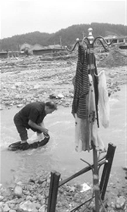 卜成嘉在浑浊的河水中洗衣服。