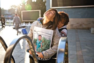 昨日，“小粽子”的家人捧着他的照片站在校门口。10月23日，“小粽子”因在玩耍时弄伤同学被罚站，回家后跳楼身亡。新京报记者周岗峰摄