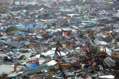 10日，在菲律宾中部莱特省的塔克洛班市，灾民站在被台风“海燕”摧毁的房屋废墟中间。新华社发