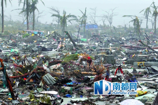 下图:11月10日，在菲律宾中部莱特省的塔克洛班市，一名灾民站在被台风摧毁的废墟中间。CFP图
