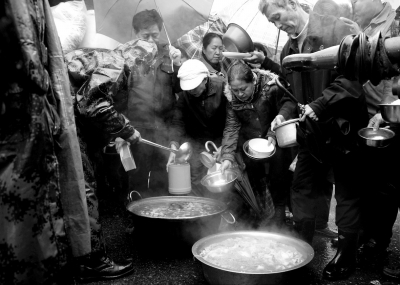 11月24日，在青岛黄岛区刘公岛路，济南军区某部官兵为群众盛热汤。新华社发