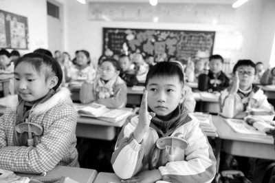 11月25日，青岛开发区崇明岛路小学三年级二班学生在举手回答老师提问。新华社发