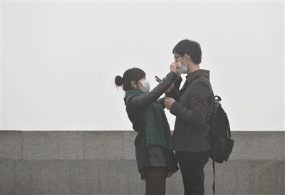 8日，上海外滩，一位女士为男友整理口罩。新华社发