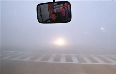昨晨，南京公交车外的路况由于大雾变得模糊不清。新华社发