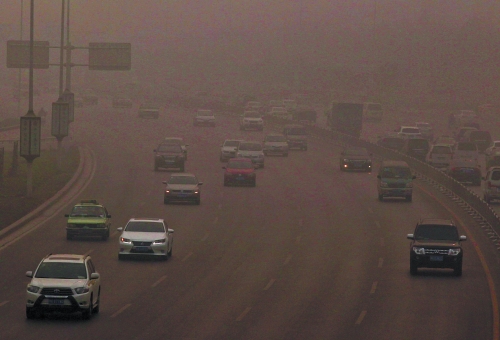 昨天的郑州街头，汽车在雾霾中“瞪着眼睛”。