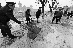 由于北京站返京客流较多，为防止路过的人摔倒,昨天一大早，东城城管大队的队员就与志愿者走上街头和过街天桥，一起清扫积雪。首席摄影记者 吴宁/摄