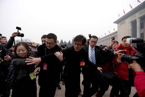 全国政协委员成龙在人群中回身试图拉住即将摔倒的媒体记者