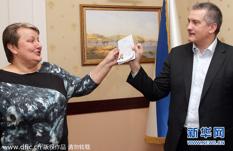 当地时间2014年3月20日，克里米亚辛菲罗波尔，克里米亚总理阿克肖诺夫正在展示新入手的俄罗斯护照。据悉俄当局正式给克里米亚居民颁发护照，民众蜂拥而至排队申请。东方IC供图