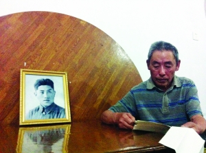 侯希贤重温父亲写给他的信，桌上摆着父亲的照片 现代快报记者 刘清香 摄