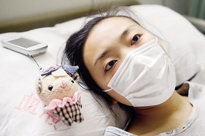 病床上，朱飞燕让心爱的卡通布娃娃陪伴自己。(资料图片）