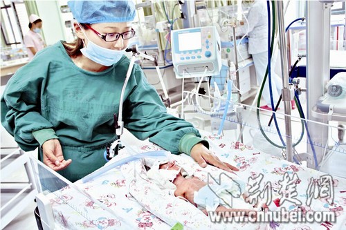 图为:妈妈赵美妮深情凝视病床上的宝宝