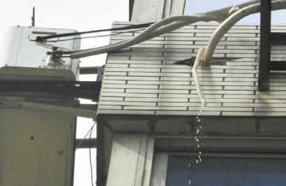 空調掛機的排水管懸在半空,冷凝水直接滴在地面上.