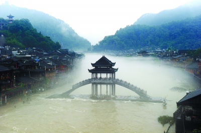 7月17日,凤凰古城沱江上升起大雾,桥梁和古城建筑在雾中若隐若现宛若