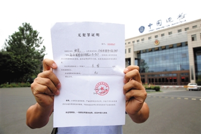 昨日,王先生出示其妻子的《无犯罪证明》新京报记者 李飞 摄