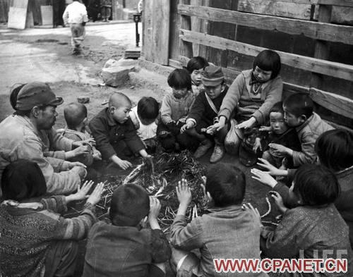   1945年9月，无家可归的孩子们在广岛郊外围成一圈烤火取暖。Alfred Eisenstaedt 摄 