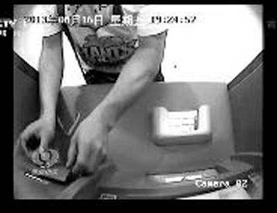 犯罪嫌疑人将“测录器”套在取款机卡槽外面，盗取银行卡磁条信息视频截图