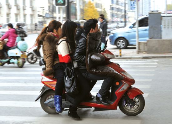 昨日,一名骑电动车的男子带着两个女士快速行驶在经二路上