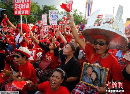 资料图：当地时间2014年5月11日，泰国曼谷，泰国“红衫军”高举英拉和他信的头像举行大规模集会。