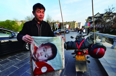 这张印有儿子的照片的旗子，是郭刚堂骑行路上的最大动力 摄/法制晚报记者 郭谦