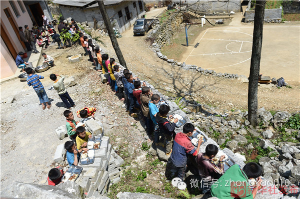 广西都安瑶族自治县拉烈镇崇业小学的学生在学校饭堂外的墙边和石头