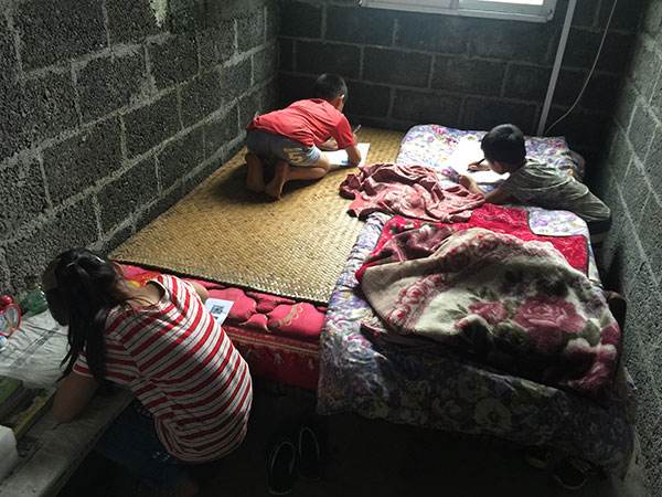 应记者的建议，渔洞村10岁的留守女童飞云和哥哥、弟弟一起趴在床上，写下对父母的思念（7月30日摄）。新华社记者 张莺 摄