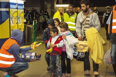 6日，德国慕尼黑，志愿者向小难民发放食物。