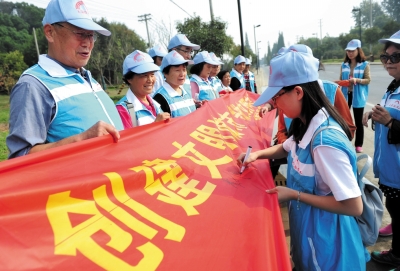 党员们徒步登上蜀冈西峰,拉起宣传横幅倡导文明,并在横幅上签名.