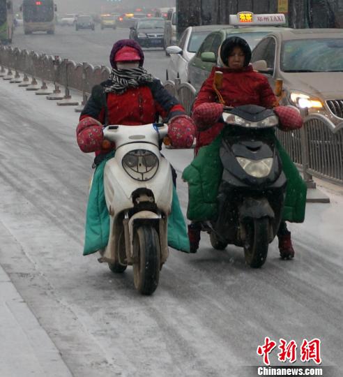 民众骑电动车在行走在湿滑的马路上 王中举 摄