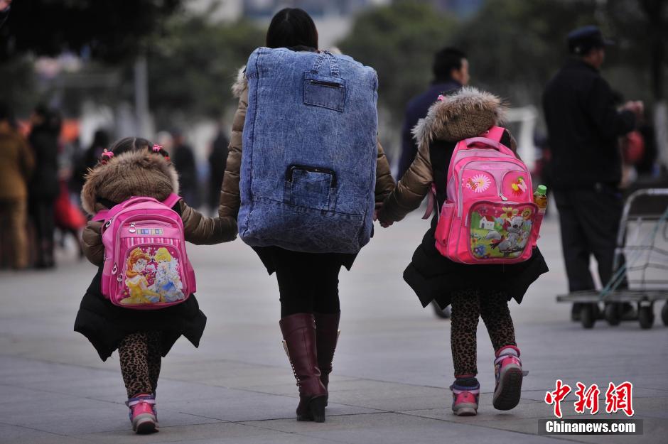 1月24日,重庆火车北站,一位母亲牵着两个女儿踏上回家路.