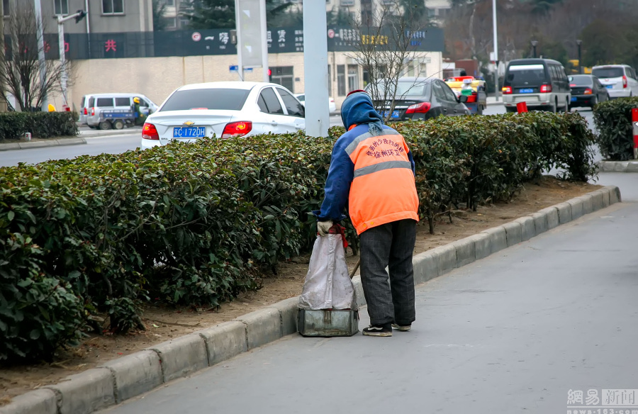 2016年2月21日,江苏省徐州市,一位年迈的环卫工老奶奶把大街上的纸屑