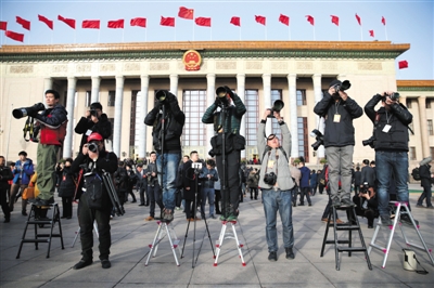 3月5日,人民大会堂外,十二届全国人大四次会议开幕,摄影记者站在梯子上拍摄代表入场。 新京报记者 薛珺 摄