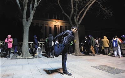 6时许 新京报首席记者陈杰在活动身体。他凌晨2时已到会场外等候。新华社发