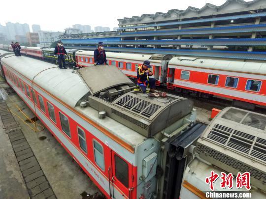 在成都车辆段存车场内,工作人员登上车厢顶部进行空调外机清洁维修