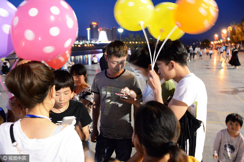 汉江公园的休闲广场上,几名二十岁左右的年轻男女,手拿众多气球,胸前