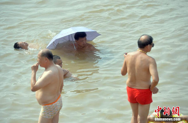 15日,高温再袭武汉,民众打伞游泳。(图片来源:中国新闻网)