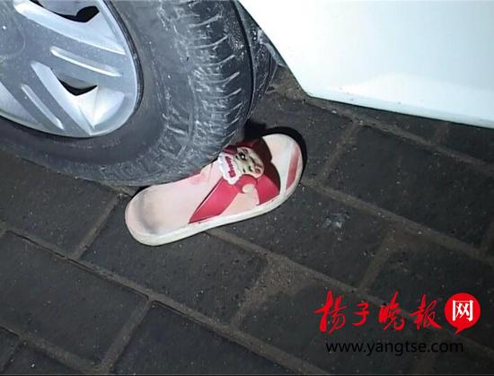女孩所穿一只拖鞋散落在小区地面。