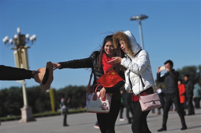 10月31日,天安门广场,一位游客伸手接过刚刚被大风吹走的帽子。新京报记者 薛珺 摄