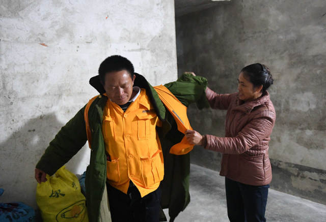 在廖成根出门去工作前,妻子在给他整理衣服(12月6日摄)。