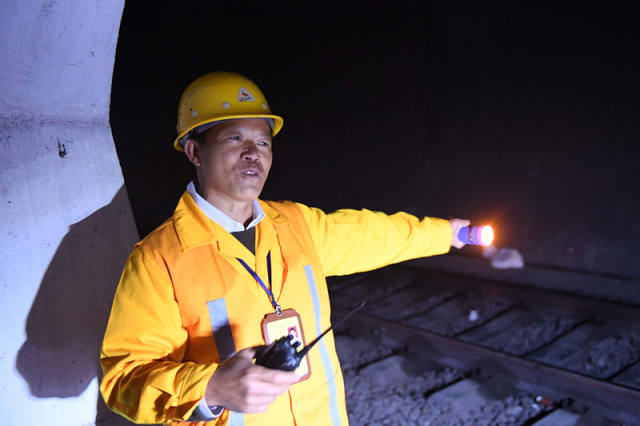 廖成根在邓山隧道内给即将驶来的列车打信号灯(12月6日摄)。
