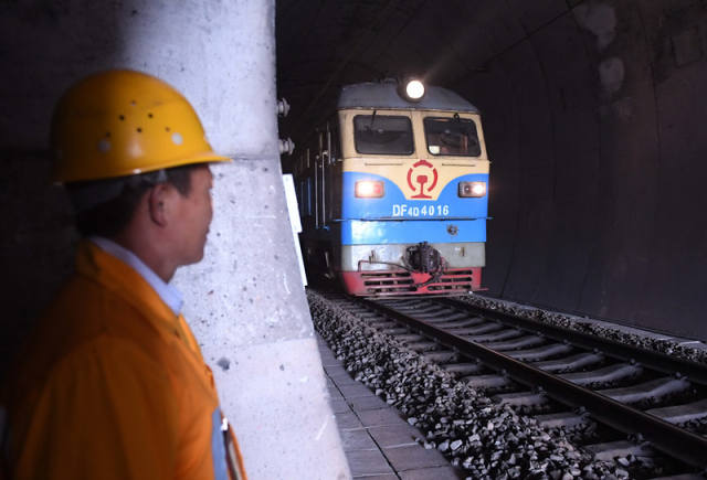 廖成根在黔桂铁路广西宜州市德胜镇境内的邓山隧道里注视列车通过(12月6日摄)。