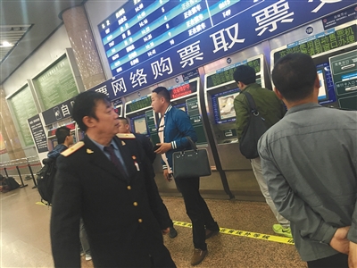 昨日，北京西站，在北广场的售票大厅内有工作人员不停巡视取票处。新京报记者王飞摄