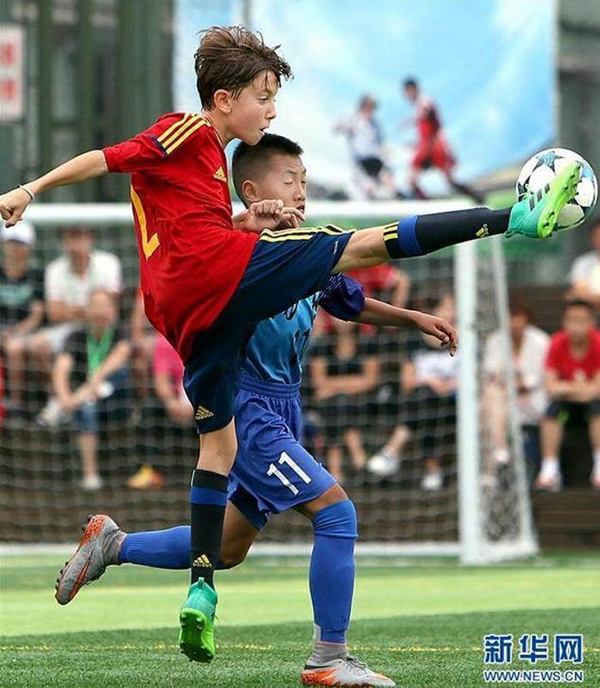 6月28日，西班牙皇家足球协会队球员（前）和上海杨浦队球员在比赛中拼抢。新华网 图